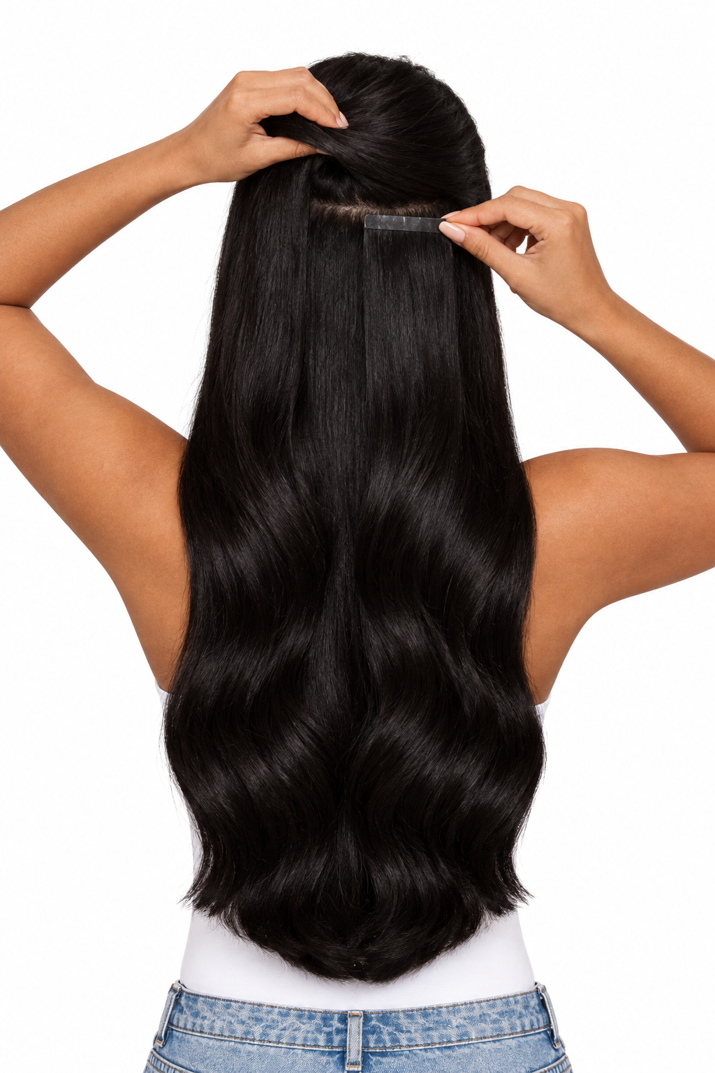 Mujer de espaldas colocándose una extensión adhesiva de pelo natural negro cerca de la raíz