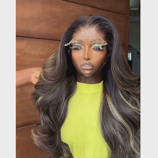 <img src="peluca_larga_ondas_balayage.jpg" alt="Peluca larga con ondas voluminosas y mechas balayage, exhibida sobre un soporte. El estilo presenta tonos oscuros con destellos rubios y un acabado brillante, ideal para un look sofisticado.">
